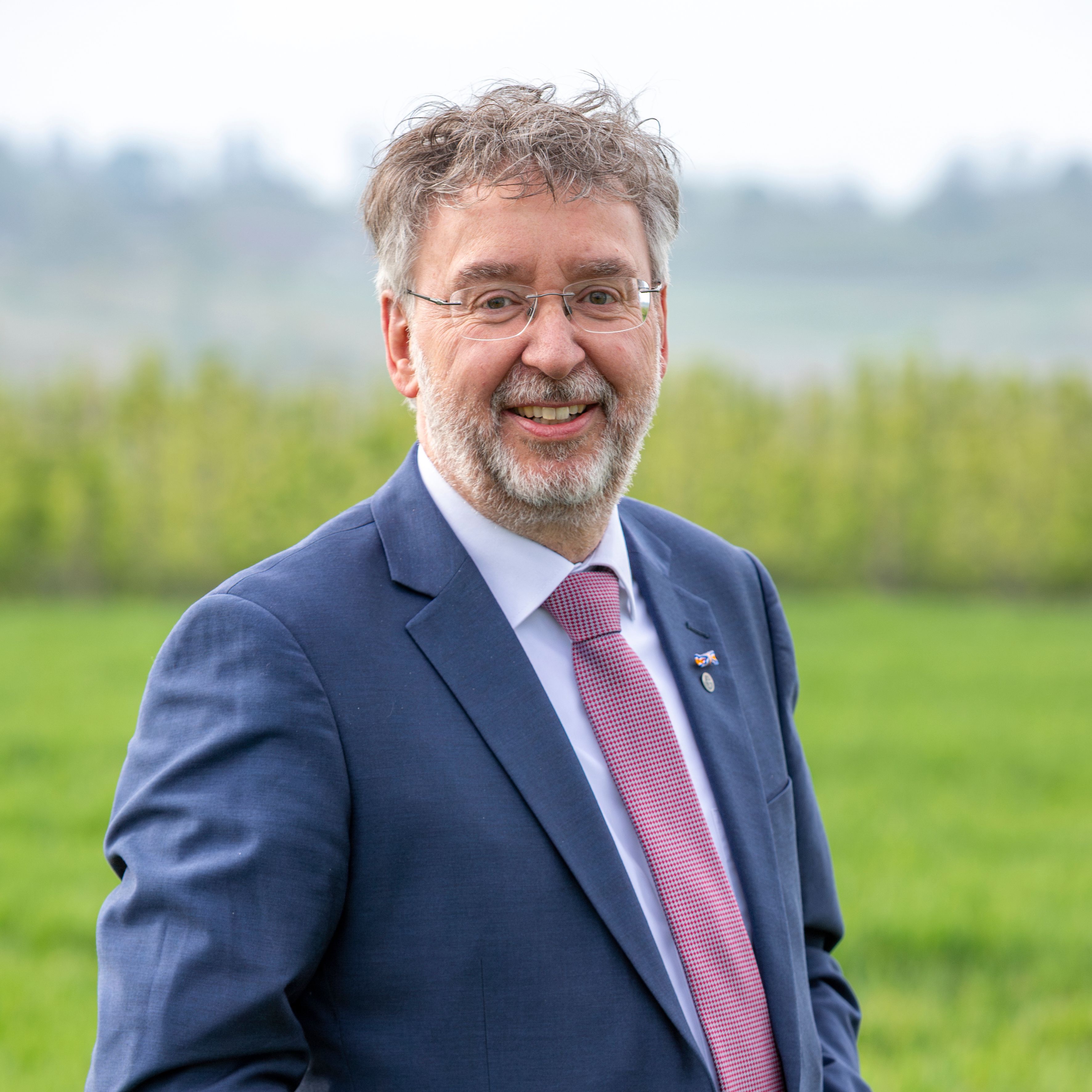 Wethouder Jos Custers staat voor een grote foto van een oud huis